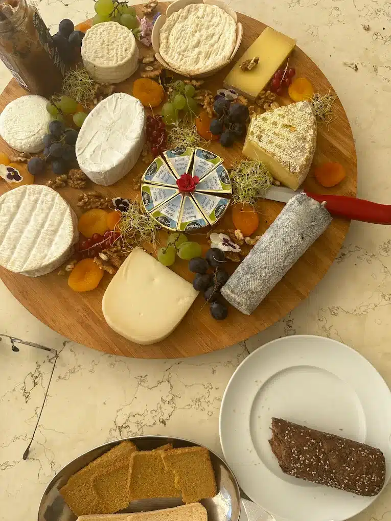 Plateau de fromages variés (chèvre, pâte molle, ferme) avec fruits, noix, et pain, incluant des portions BioVerde Nature.